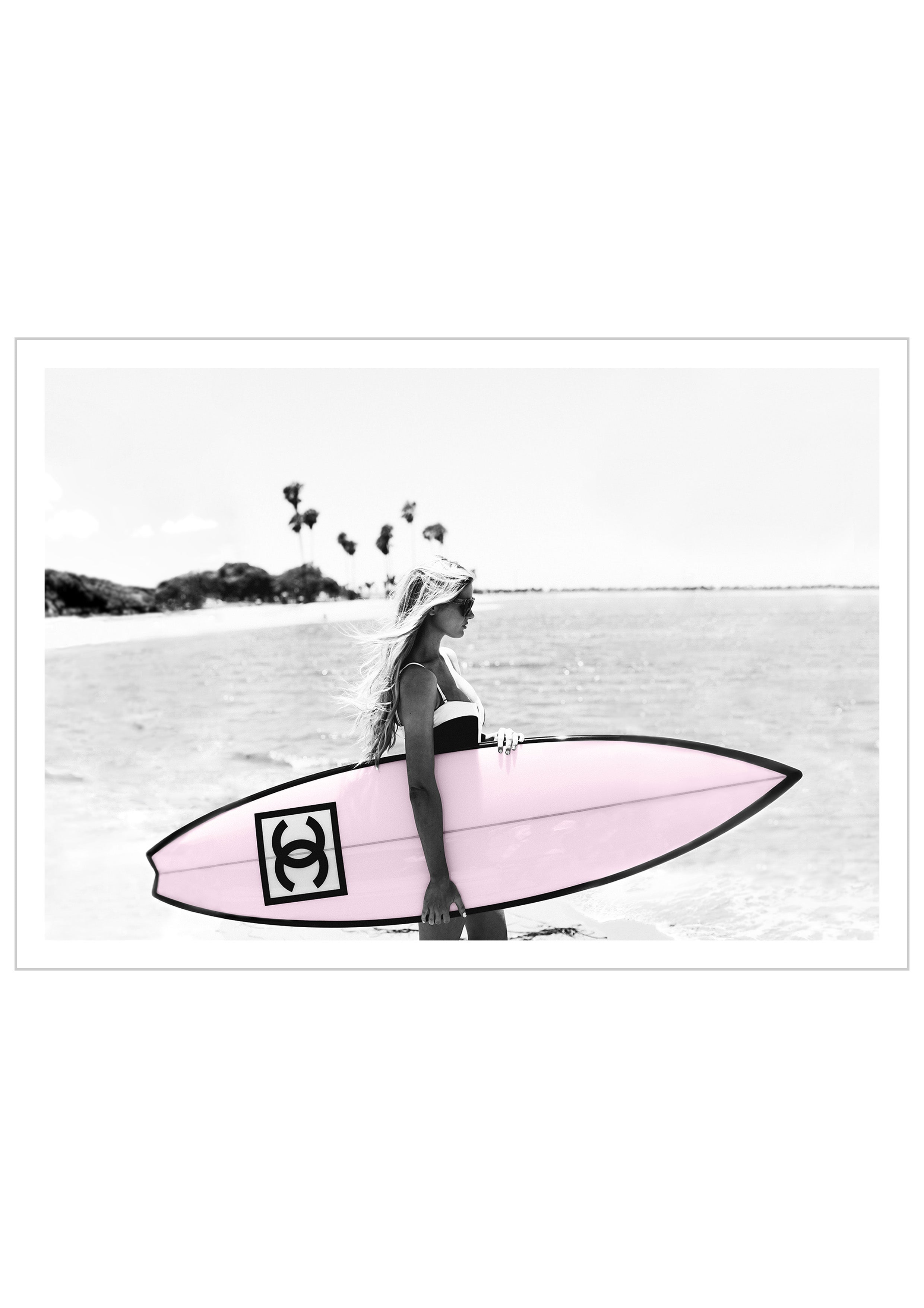 Photograph of a bikini girl holding a Chanel surfboard toward the sea.