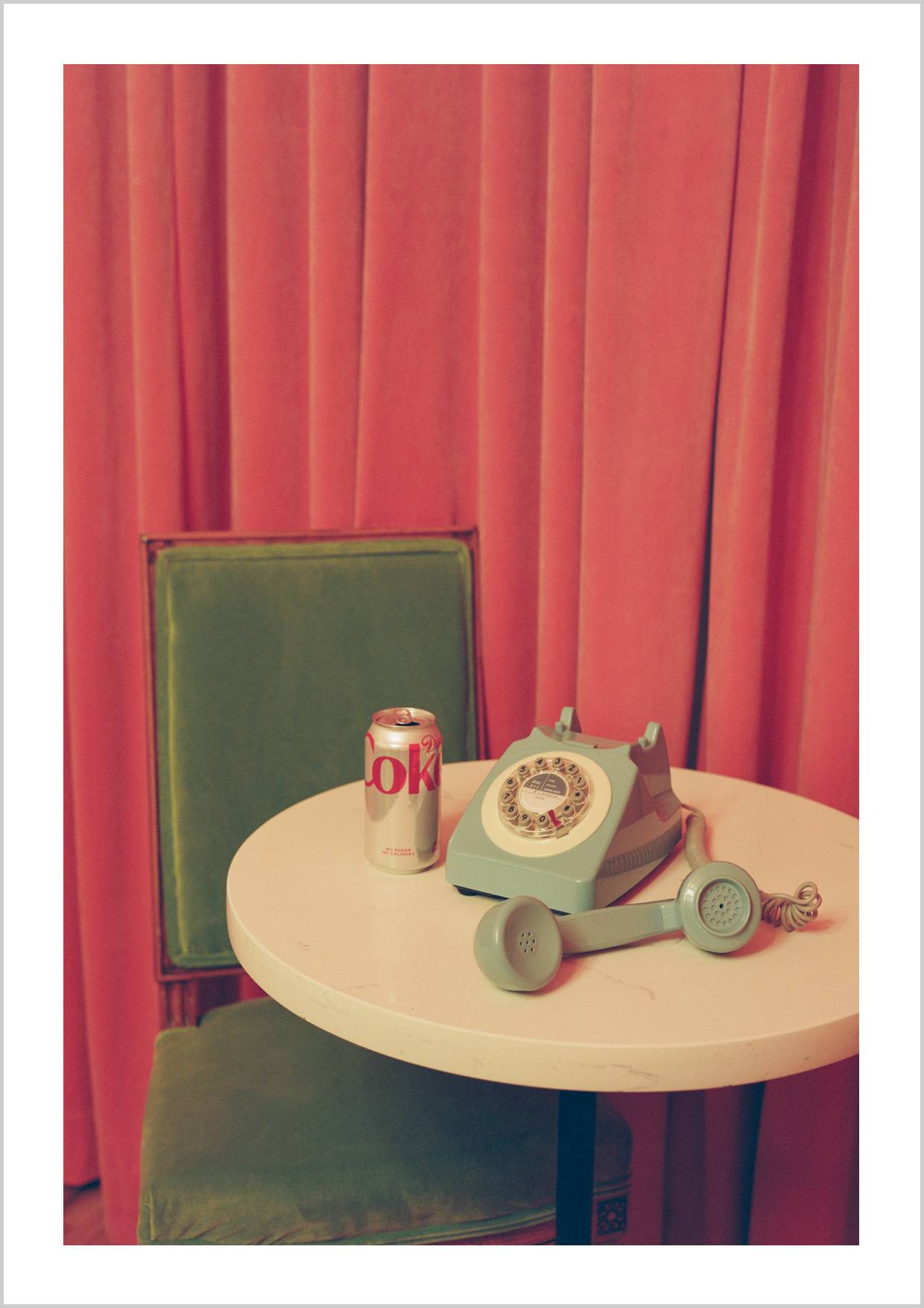 A vintage telephone and a can of Diet Coke on a table, with pink curtains in the background. – Arteve Gallery