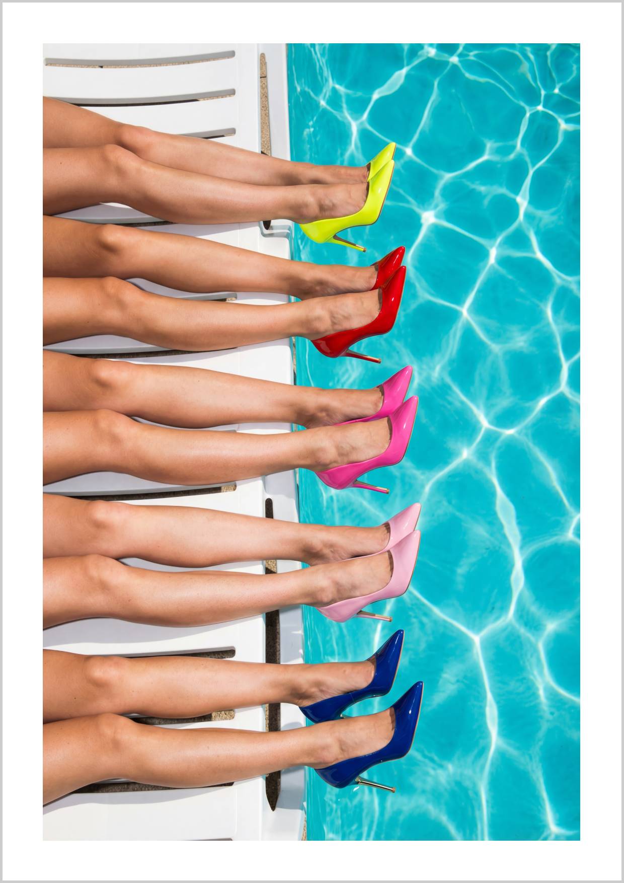 Colorful high heels lined along the edge of a pool, reflecting vibrant hues in the water. – Arteve Gallery