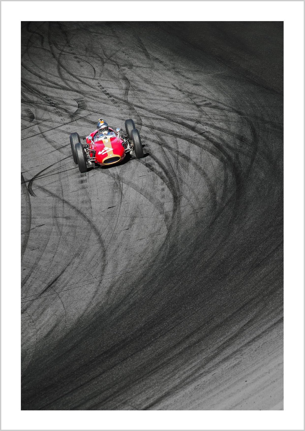 A vintage race car in motion on an asphalt track, leaving tire marks behind. – Arteve Gallery
