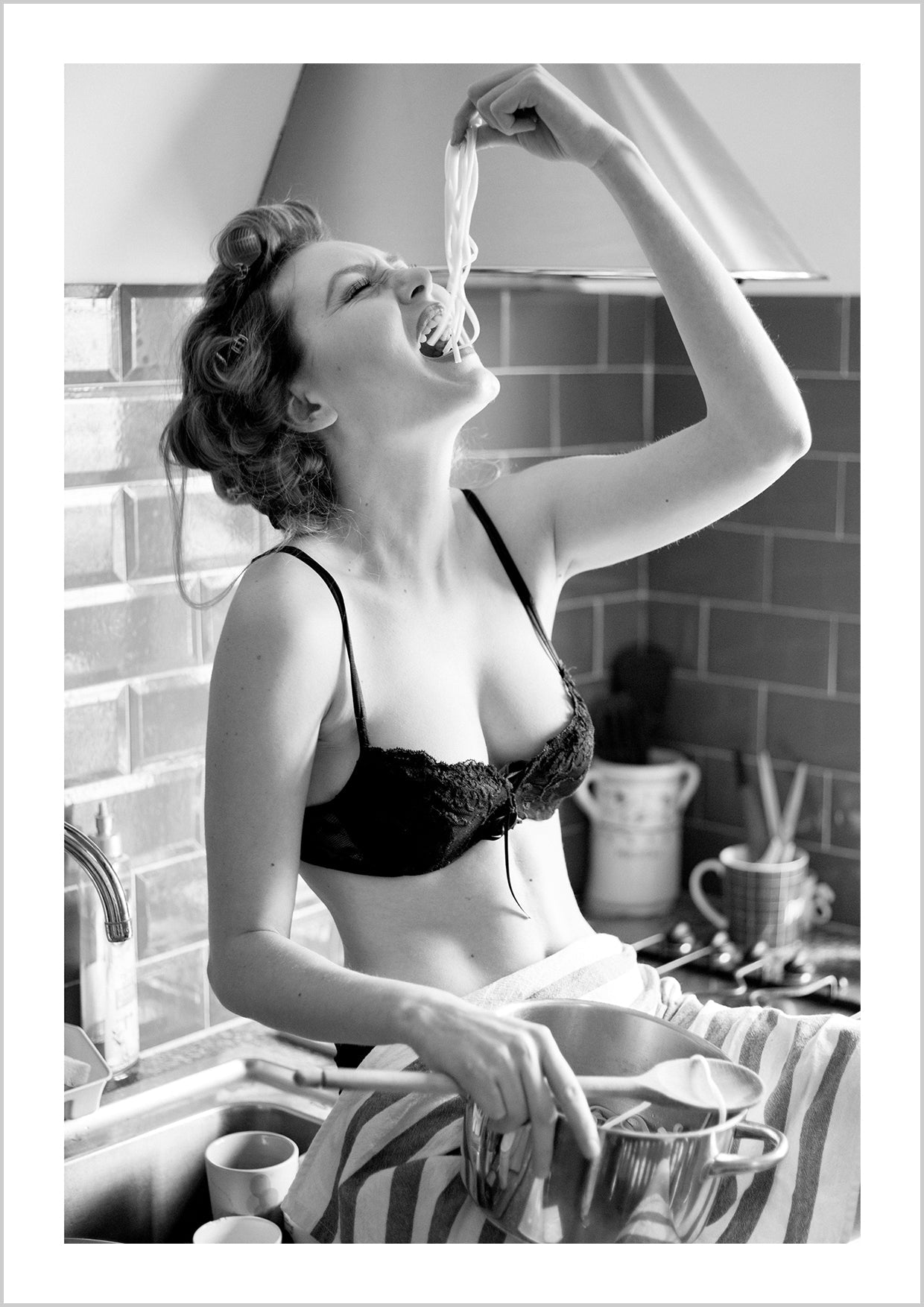 Girl in lingerie eating spaghetti with her hands in the kitchen