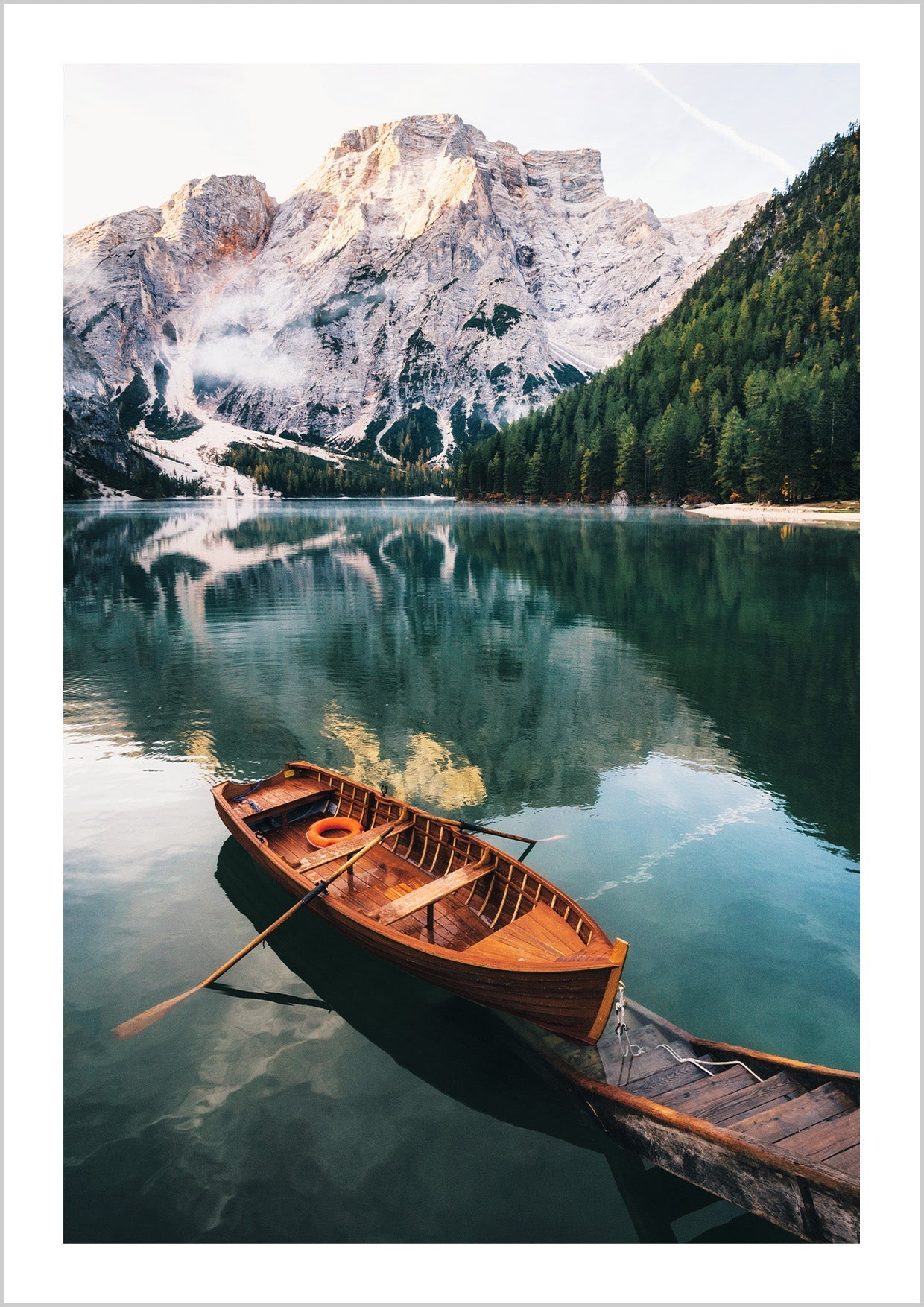 Nature poster with a photographic motif of a red canoe resting on a picturesque wooden pier on a quiet lake. On the side of the clear-blue lake, tall, ice-clad mountains are towering which is reflected beautifully on the still water surface.