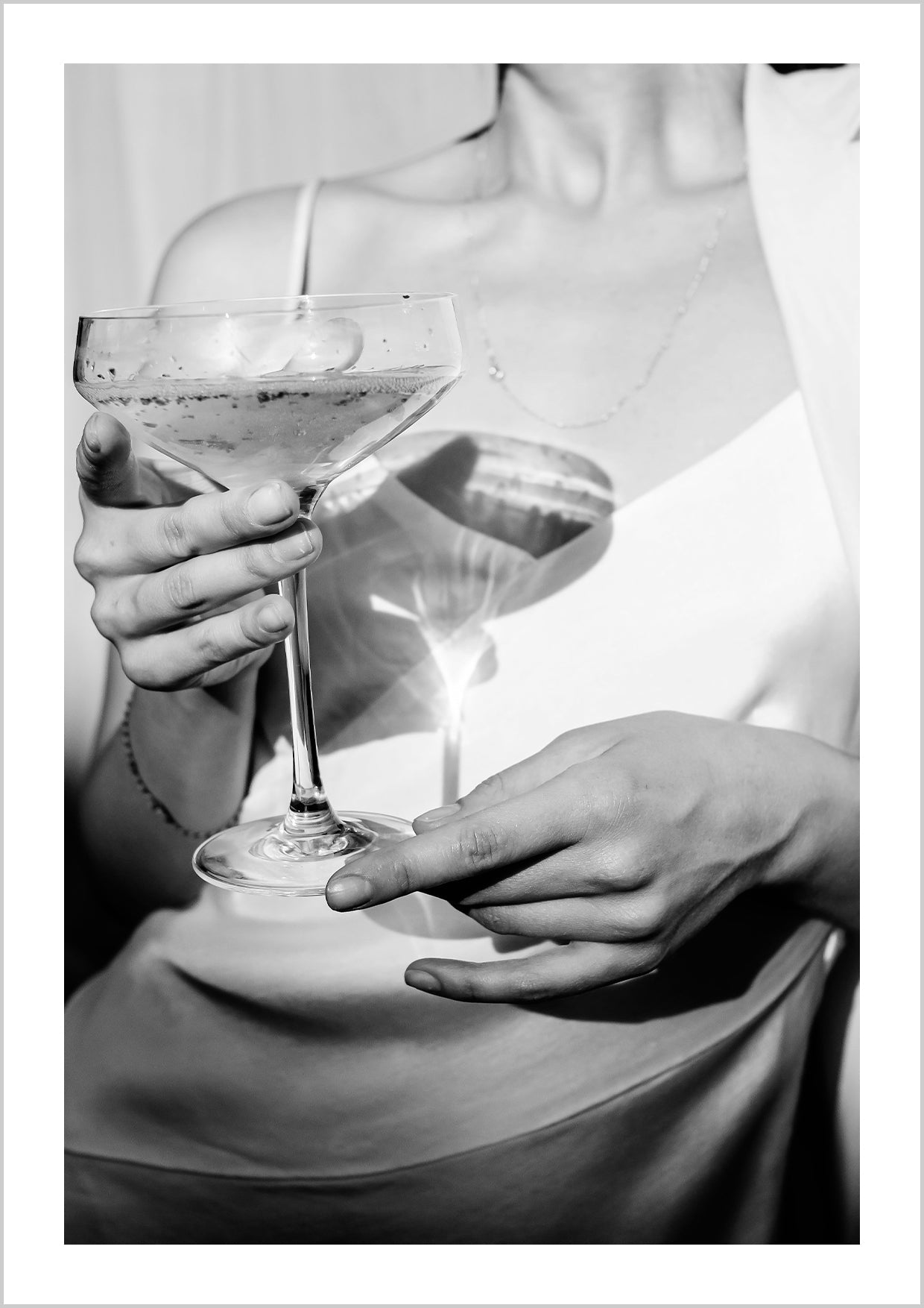 Photograph in black and white of a woman holding a champagne glass in front of her.