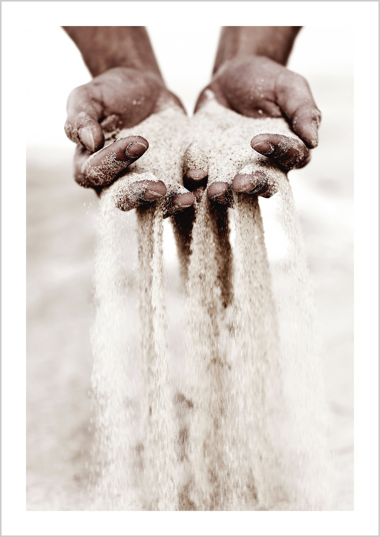 Photograph of a pair of hands holding sand that's slipping through the fingers. 