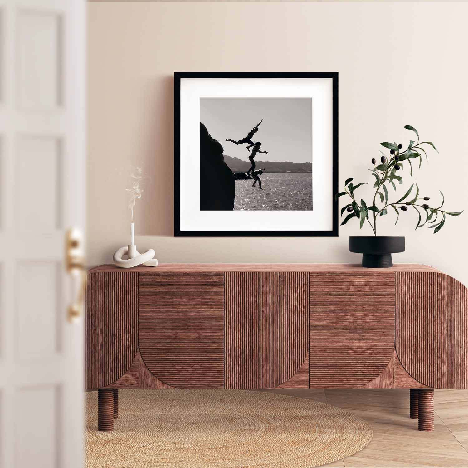 Black and white poster of 3 kids jumping into the sea from a Clift