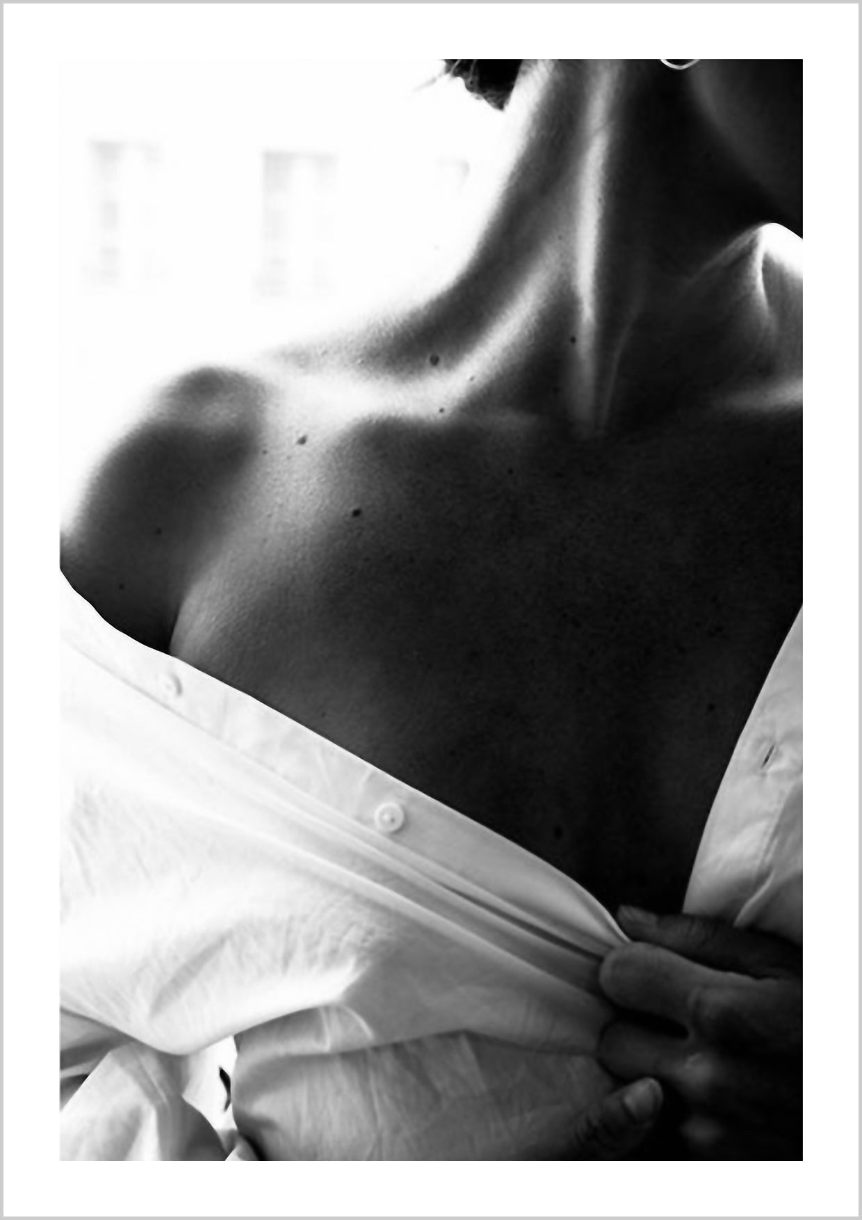 Photograph in black and white of a woman in a white shirt showing her shoulder. Sensual photo art is a style we love, and this Poster fits well with both other black and white photographs as well as botanical Posters.