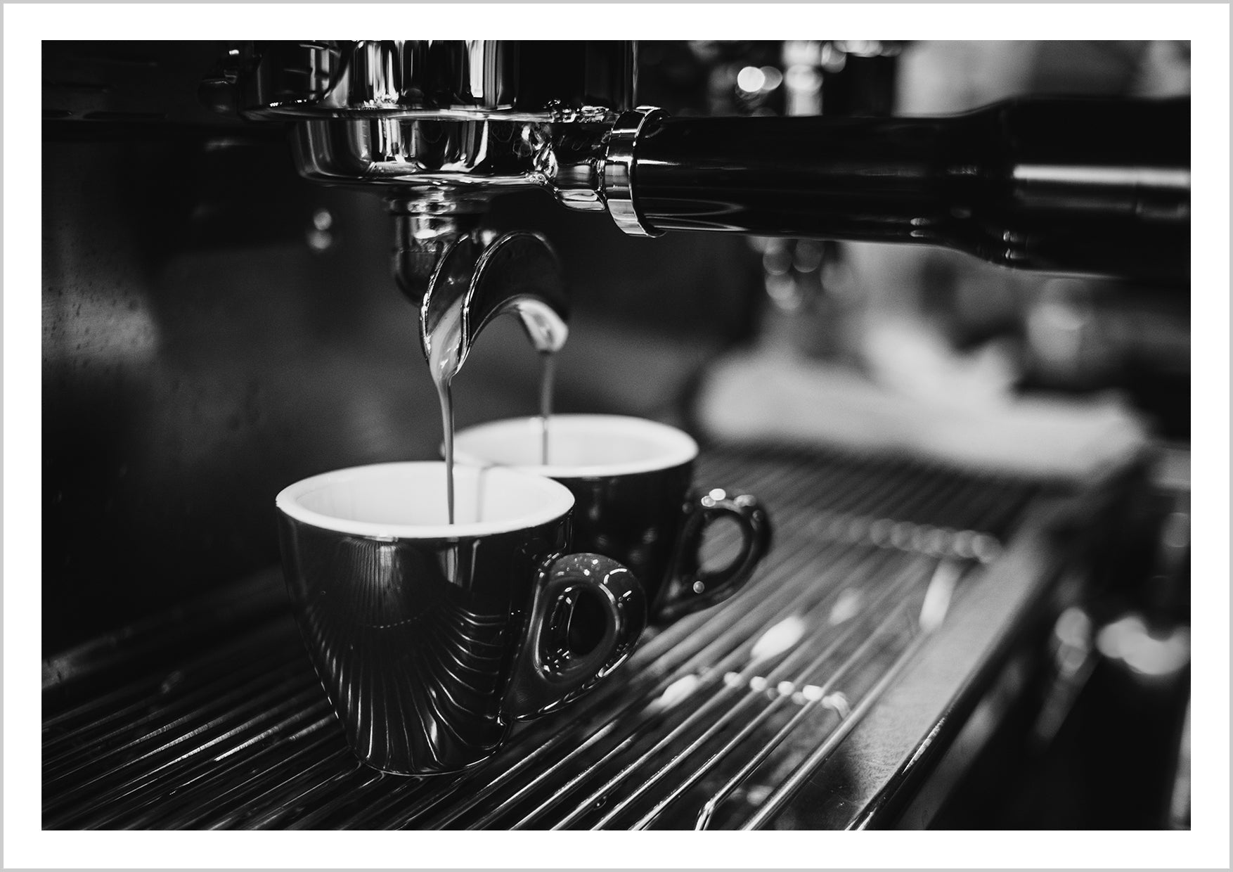 Close-up photograph in black and white of coffee dripping out of an espresso machine. This print is perfect for the coffee lover who wants to add a high-end look to their kitchen space.