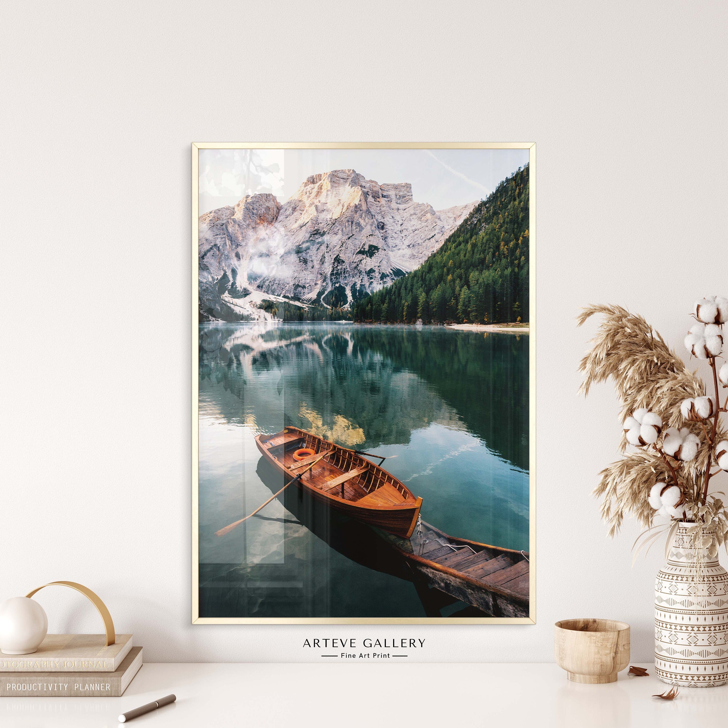Nature poster with a photographic motif of a red canoe resting on a picturesque wooden pier on a quiet lake. On the side of the clear-blue lake, tall, ice-clad mountains are towering which is reflected beautifully on the still water surface.