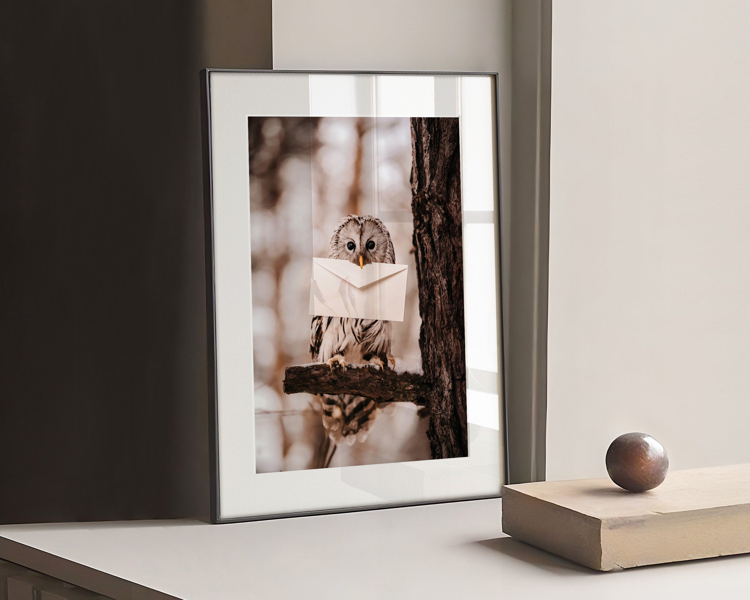 Photo Poster with an owl holding a letter. The owl is a symbol of wisdom and mystery. It's sitting on a branch and the big eyes are looking forward. Hang this Poster in your living room, bedroom, or study to let the mystical presence fill your space with wonder.