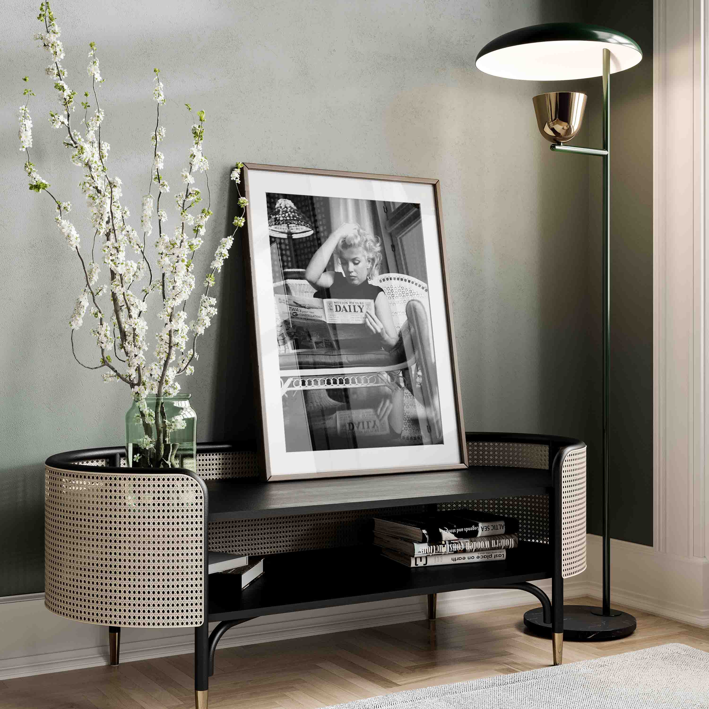 Black & White photography Poster with an iconic photo of Marylin Monroe reading a daily newspaper on the sofa at her home.