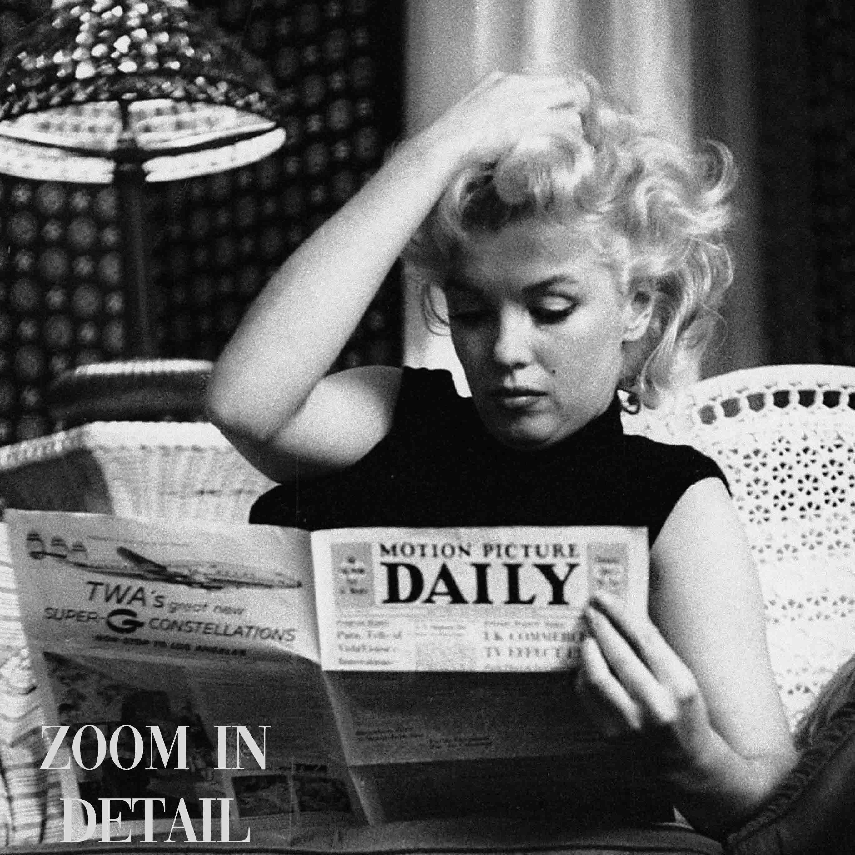 Black & White photography Poster with an iconic photo of Marylin Monroe reading a daily newspaper on the sofa at her home.