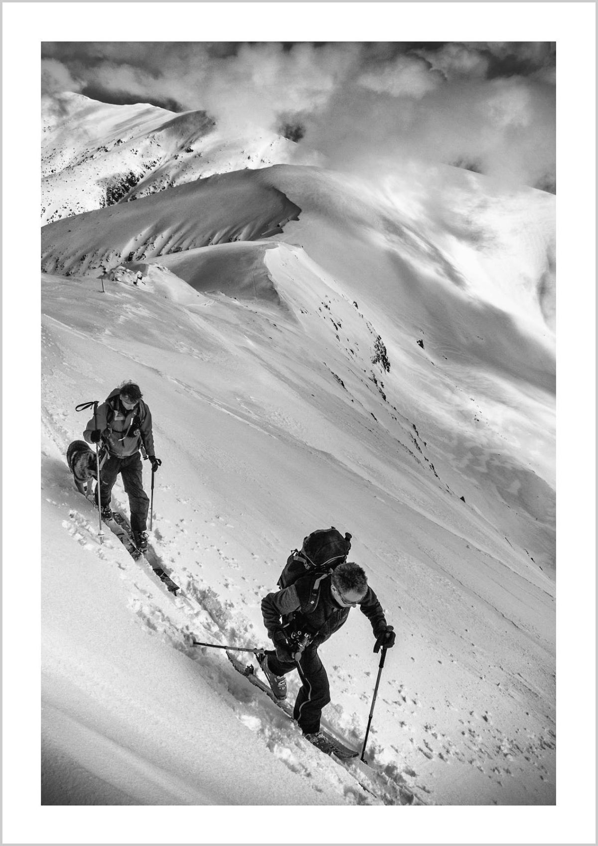 Two skiers climbing a snowy mountain slope in black and white. – Arteve Gallery