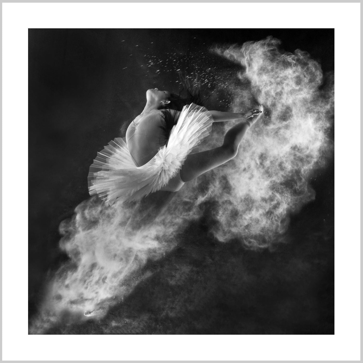 A dancer in a white tutu leaps gracefully, surrounded by swirling white powder against a dark background. – Arteve Gallery
