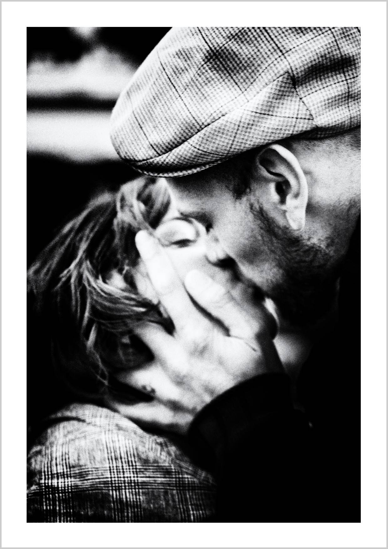 A close-up of a couple embracing and kissing, with one hand gently holding the other's face, set in black and white. – Arteve Gallery