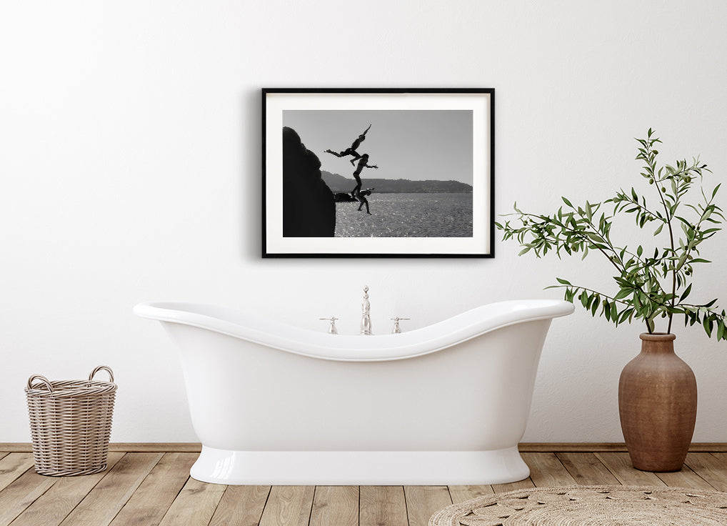 Black and white poster of 3 kids jumping into the sea from a Clift